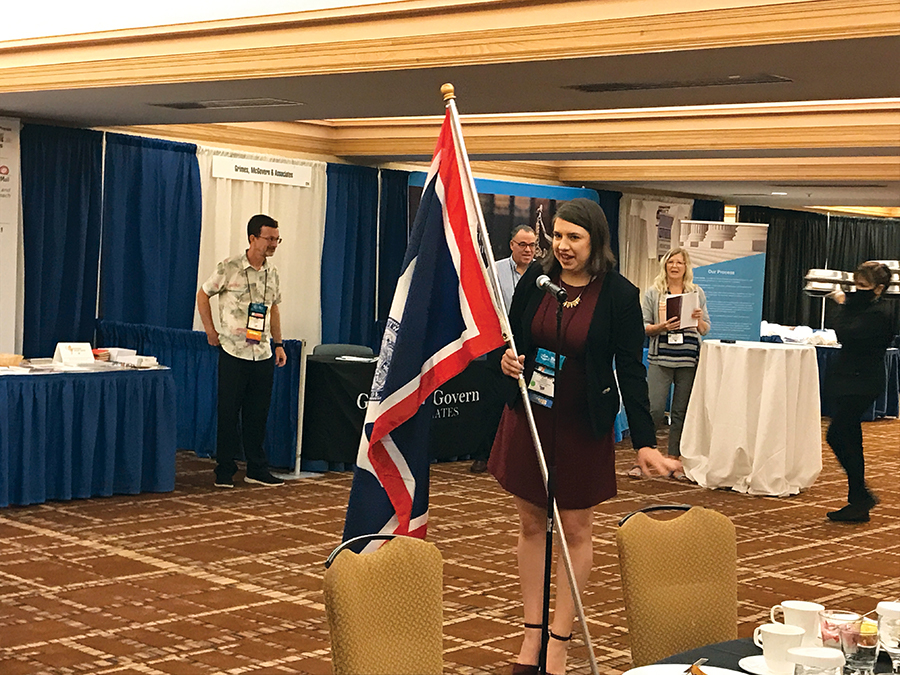 Katelyn Mary Skaggs, reporter, Leader Publications, Festus, Missouri, carries the Wyoming flag for the Adelman family during the Friday morning opening breakfast of convention.