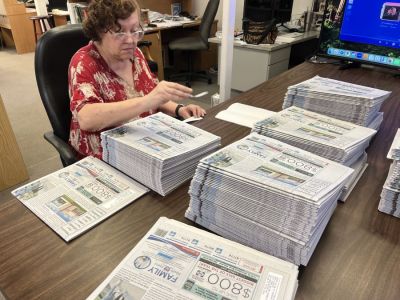 Paula Tigges, one of the first employees to come to work for the newspaper once its three founders were able to hire staff in 1993, applies mailing labels to hundreds of newspapers.