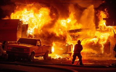 A Wenatchee Valley Firefighter begins an attack on a fire that engulfs a fifth wheel trailer, truck, and damages two houses at the northwest corner of 13th Street Northeast and Clements Circle in East Wenatchee Sunday night, April 30, 2023, at about 9:30. (Don Seabrook | The Wenatchee (Washington) World -- This photo was the winner of the News category of the Pub Aux Photo Contest, third quarter, 2023.)